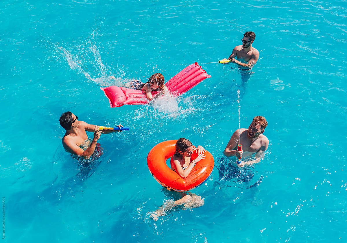 A family having fun playing with pool toys and floaties in a pool