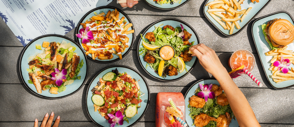 Assorted tropical dishes, salads, burgers, and cocktails served poolside at Blue Flamingo Resort Key West.