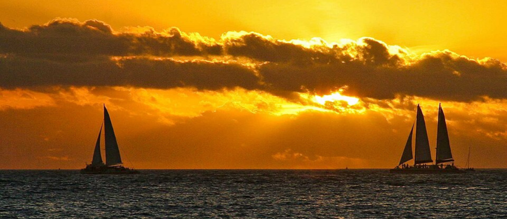 A sailboat silhouetted against an orange sunset over the water in Key West