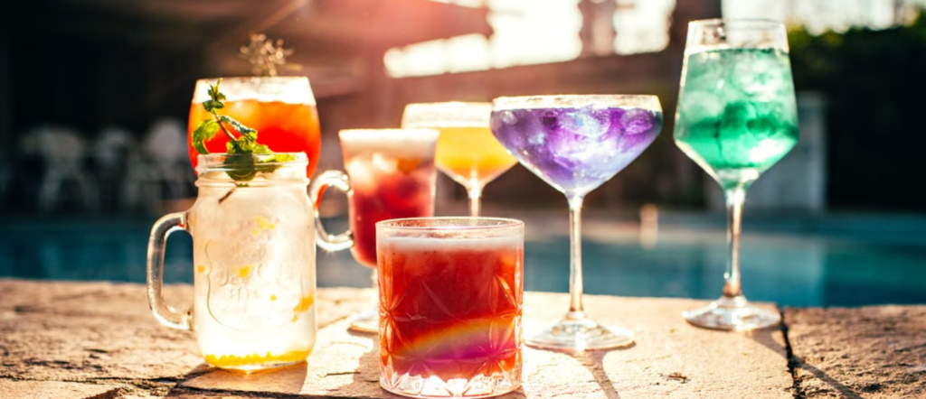 Colorful tropical cocktails arranged beside a swimming pool in bright summer sunshine