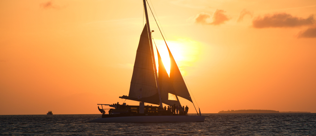 Sailboat silhouetted against a vibrant orange sunset over the ocean in Key West, Florida