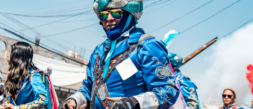 Festival performers wearing vivid costumes and feathered headdresses during an outdoor parade