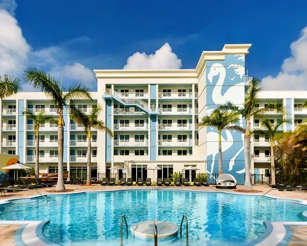 Outdoor pool at Blue Flamingo Resort Key West with palm trees and a large flamingo mural on the hotel.