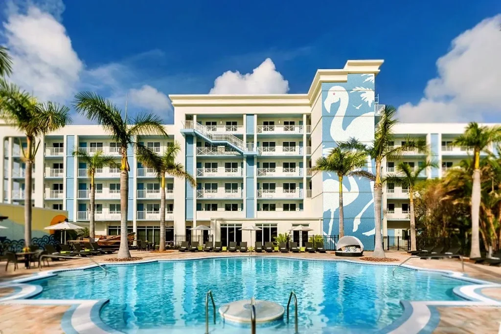 Outdoor pool at Blue Flamingo Resort Key West with palm trees and a large flamingo mural on the hotel.