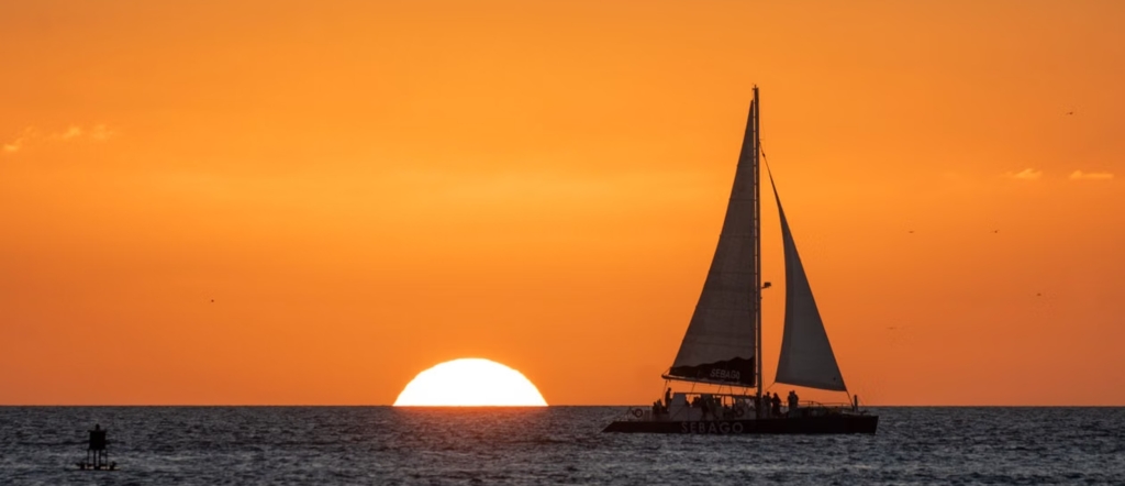 Wide Key West street lined with colorful storefronts, palm trees and historic architecture