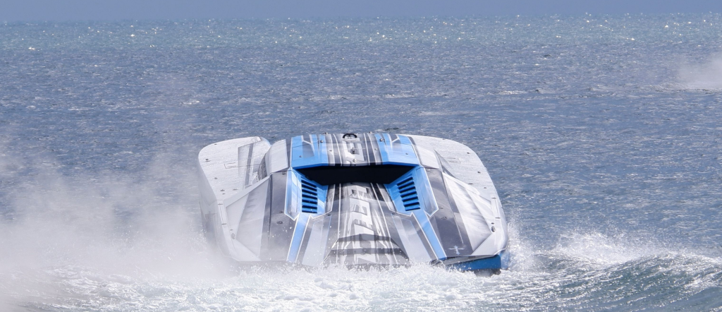 White and blue powerboat speeding across the ocean and producing a trail of spray