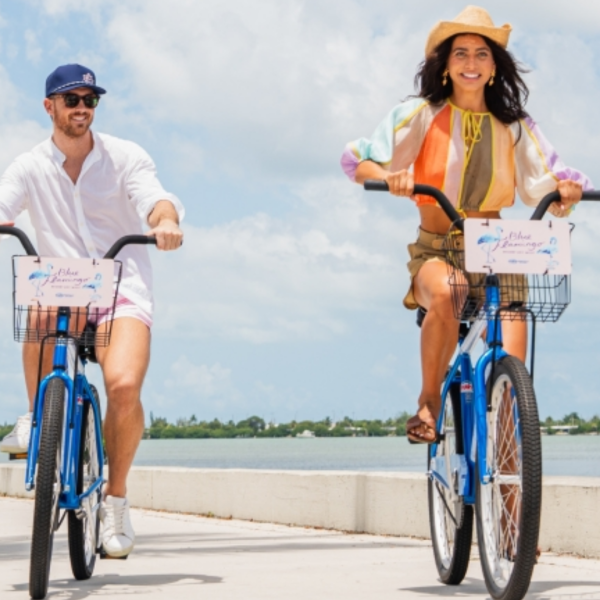 Couple riding Blue Flamingo bicycles along a palm-lined waterfront path in Key West